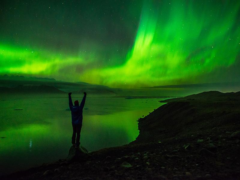 The image features astrophotographer Jack Fusco posing in front of the Northern Lights. 