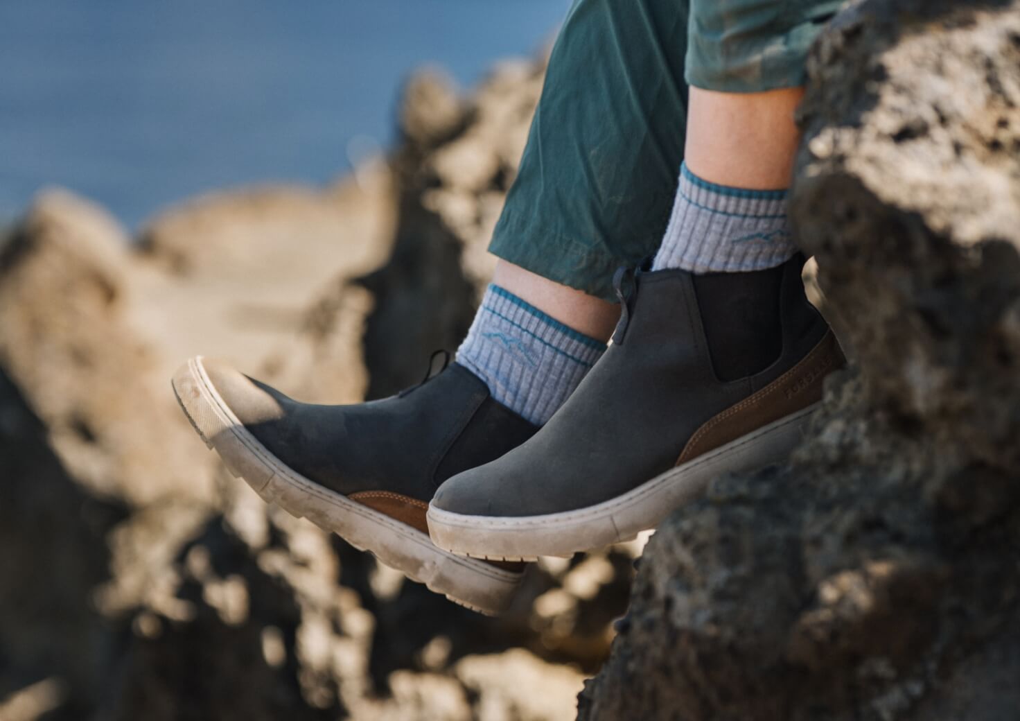 Shop Forsake women's featuring a woman sitting off a cliff in the Lucie Chelsea in black.