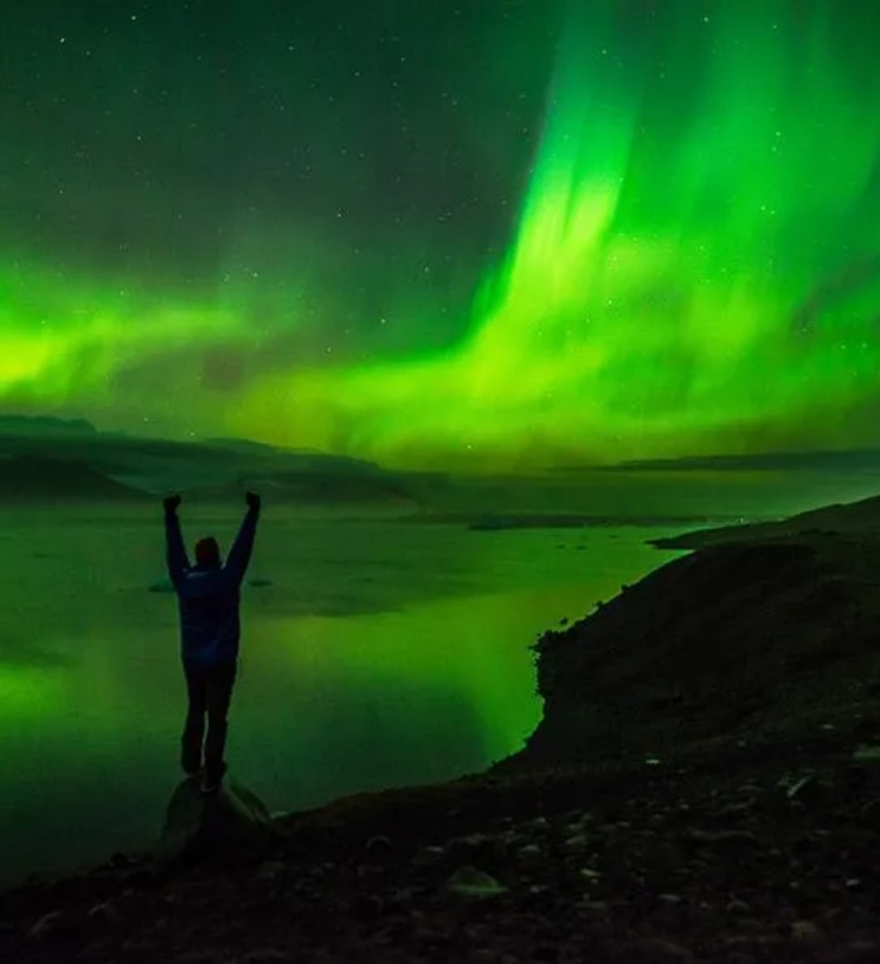 The image features astrophotographer Jack Fusco posing in front of the Northern Lights. 
